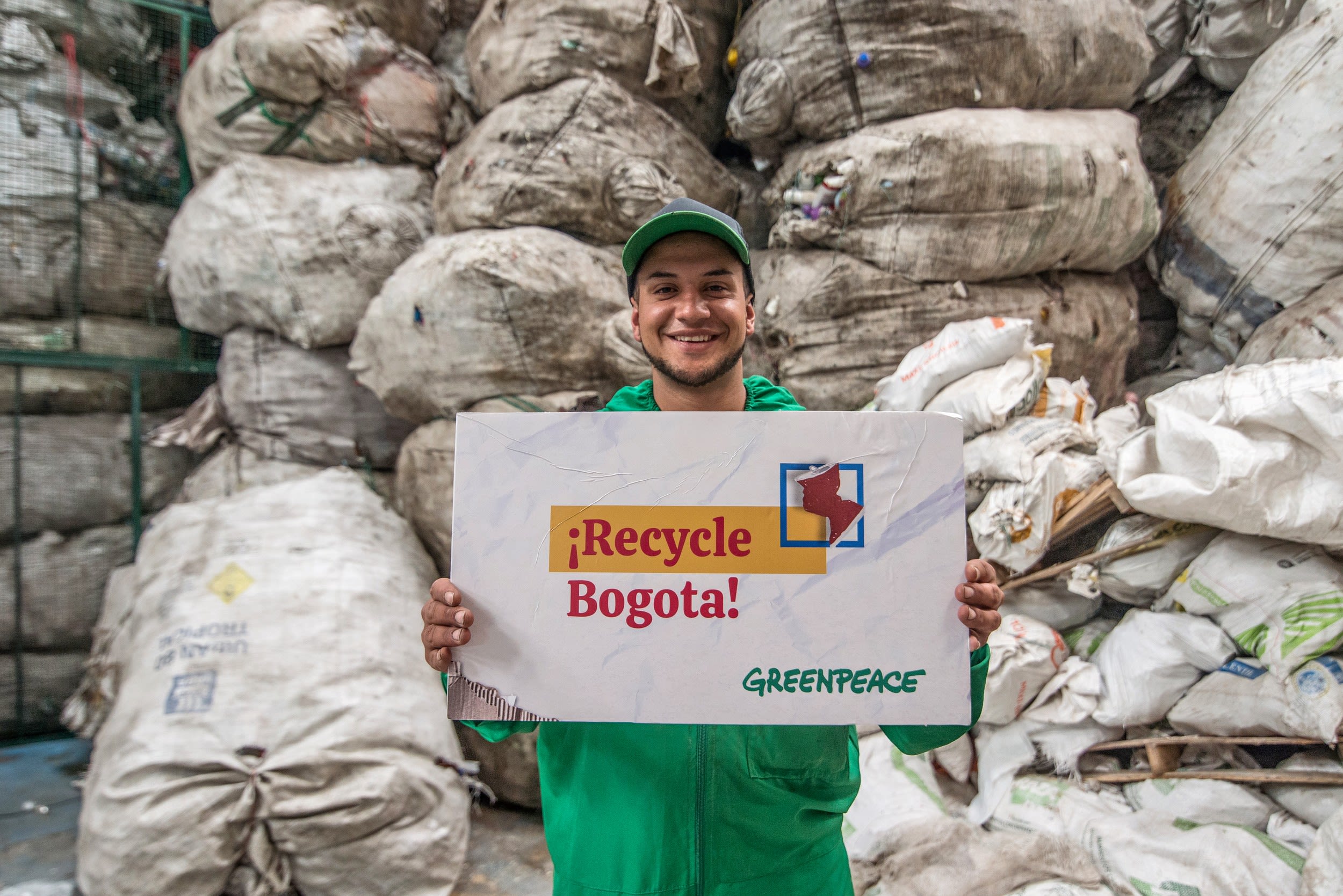 A worker at a  Waste Management and Recycling in Bogotá, Colombia holds a sign reading 'recycle bogota'